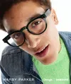 The image shows a man wearing dark green Google intelligent eyewear frames by Warby Parker.